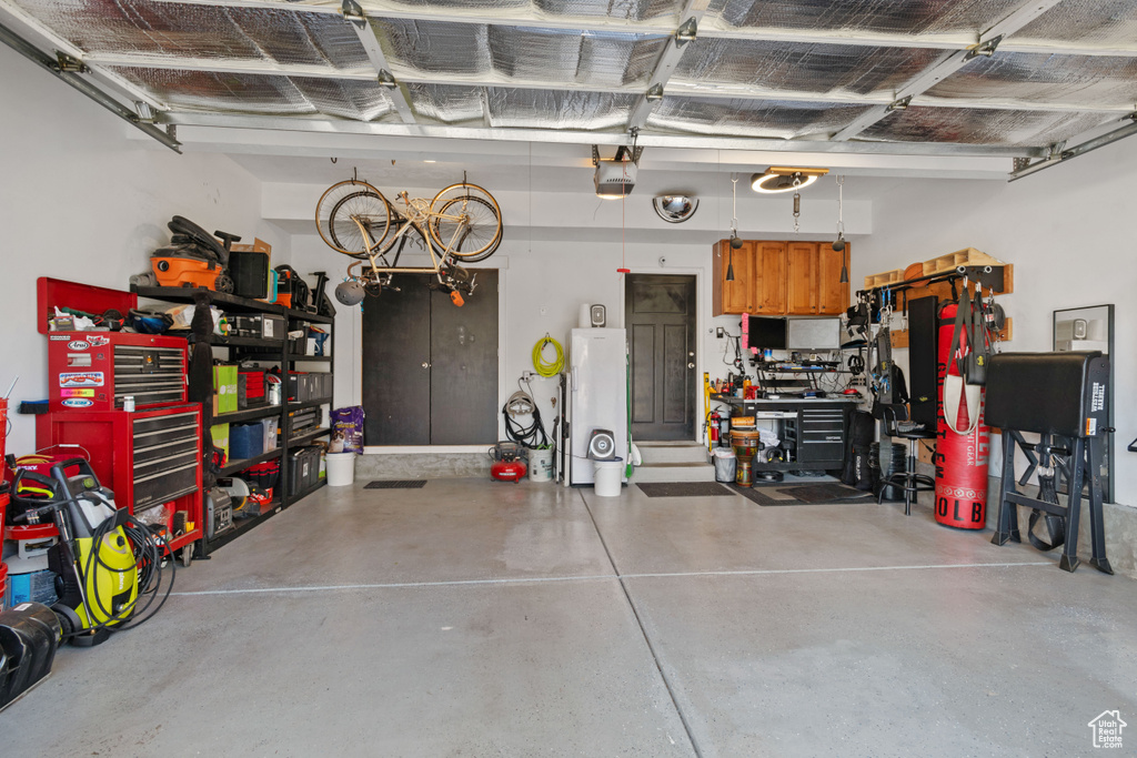 Garage with water heater, a garage door opener, and a workshop area