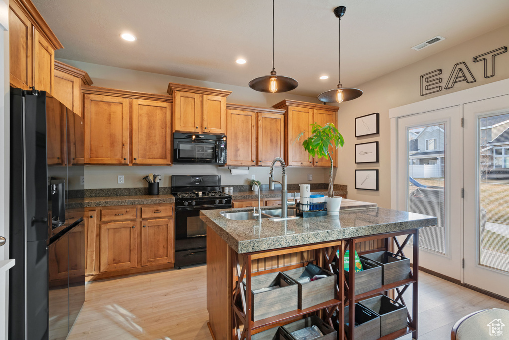 Kitchen with a sink, black appliances, light wood finished floors, and recessed lighting