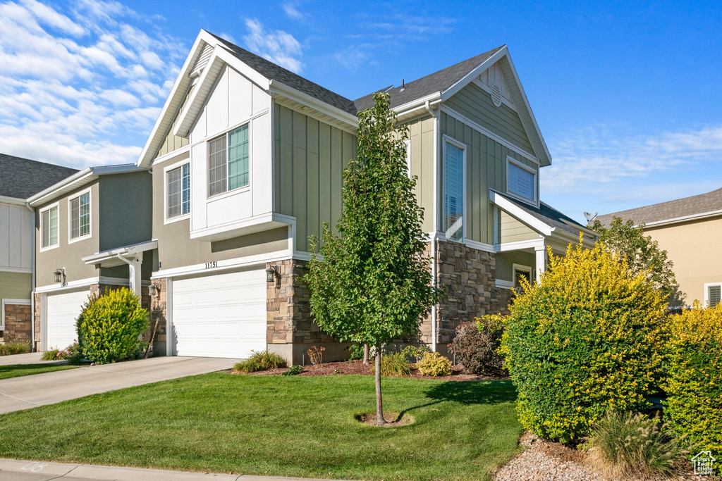 View of front of house featuring stone siding, a garage, and board and batten siding