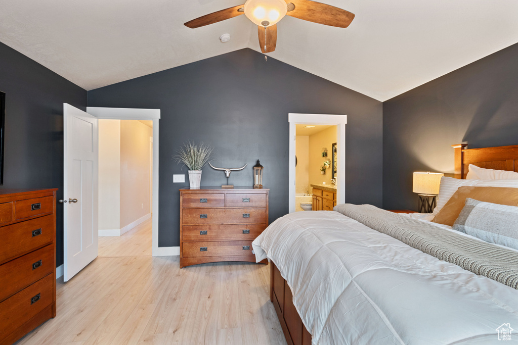Bedroom with light wood finished floors, baseboards, connected bathroom, a ceiling fan, and vaulted ceiling