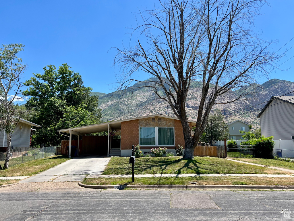 View of front of home featuring a mountain view, concrete driveway, brick siding, and a carport