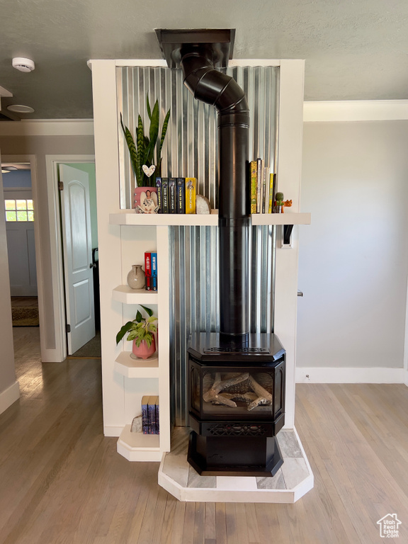 Detailed view of a wood stove, wood finished floors, a smoke detector, and baseboards