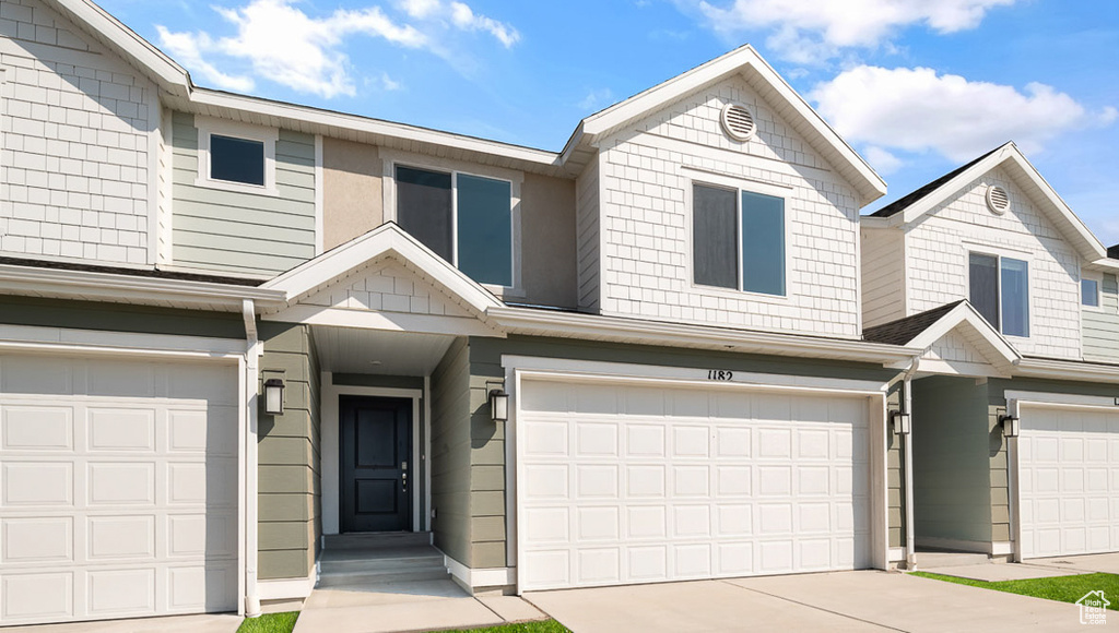 View of property featuring an attached garage and concrete driveway