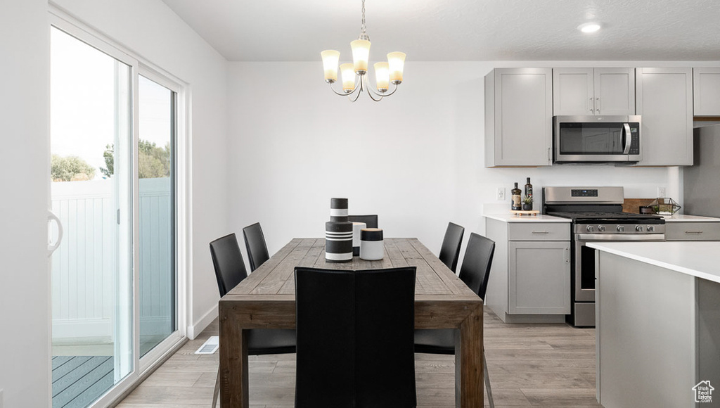 Dining space with light wood-type flooring and a notable chandelier