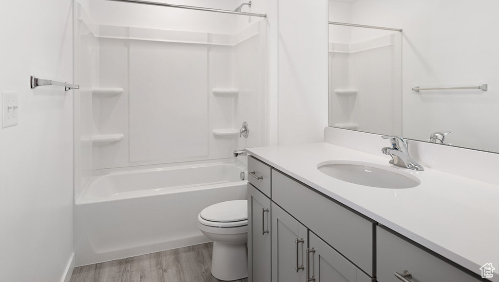 Bathroom featuring tub / shower combination, toilet, vanity, and wood finished floors