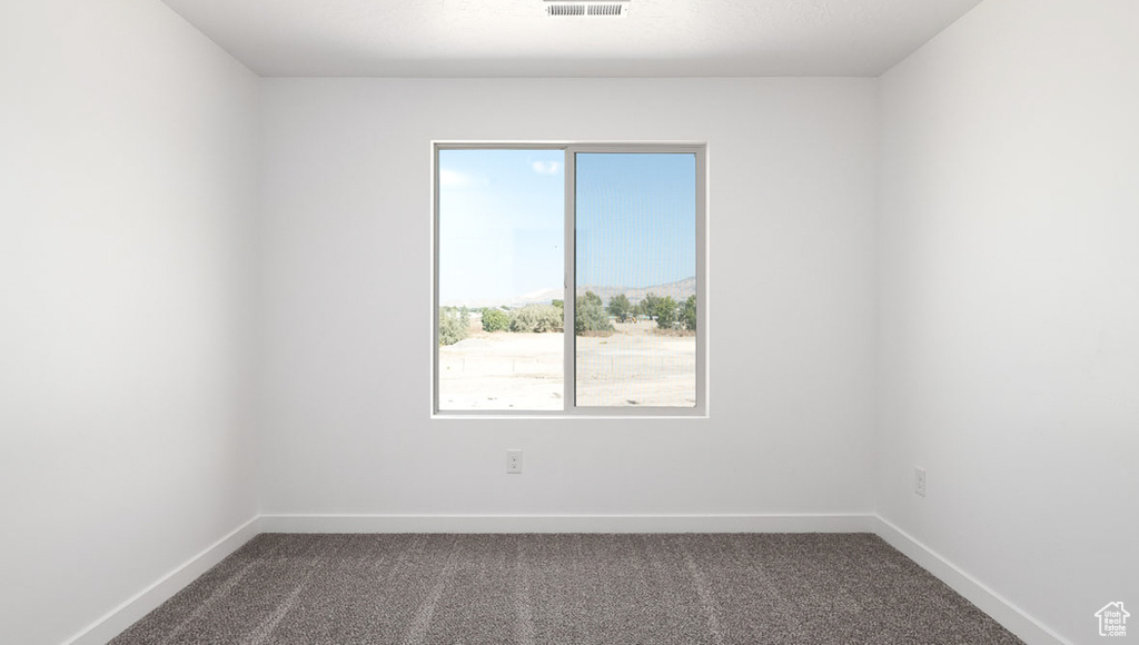 Empty room with baseboards, visible vents, and dark carpet