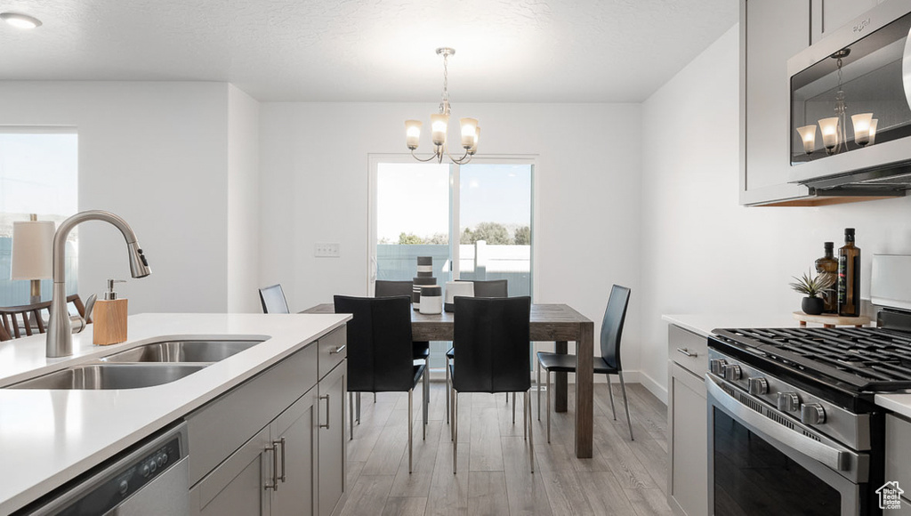 Kitchen featuring light countertops, a sink, an inviting chandelier, and appliances with stainless steel finishes