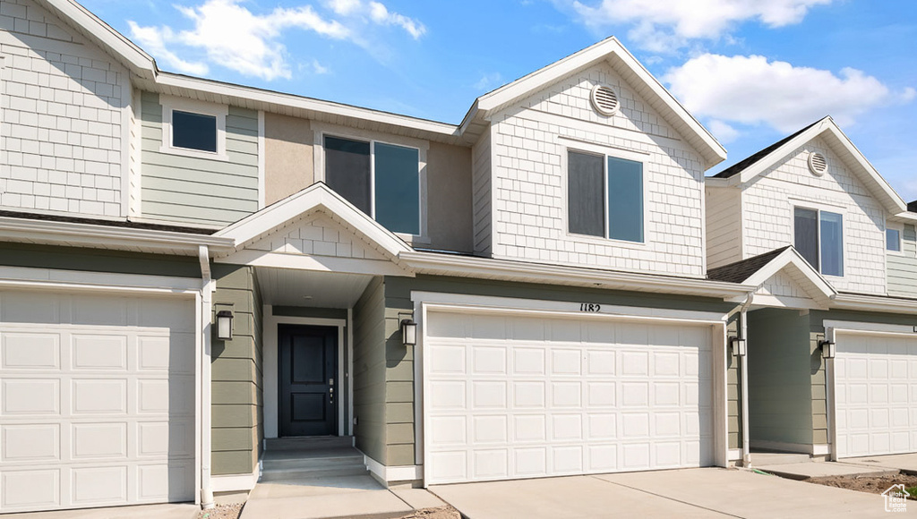 Townhome / multi-family property featuring an attached garage and concrete driveway
