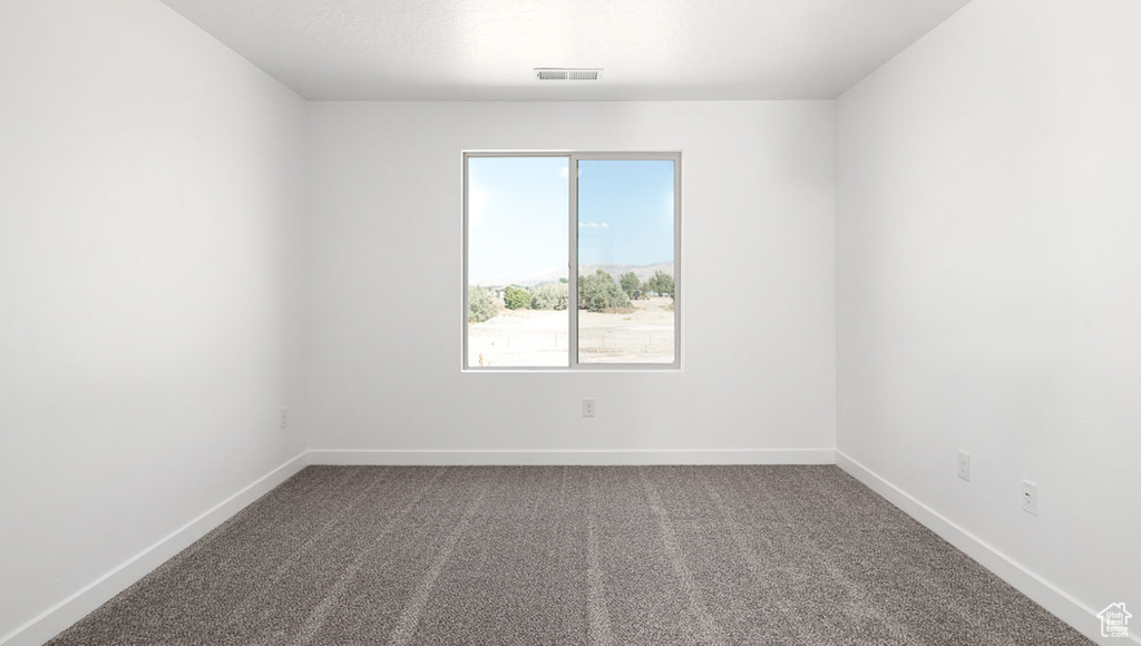 Carpeted spare room featuring baseboards and visible vents