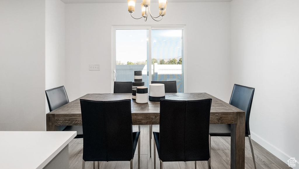 Dining area with baseboards, a chandelier, and wood finished floors
