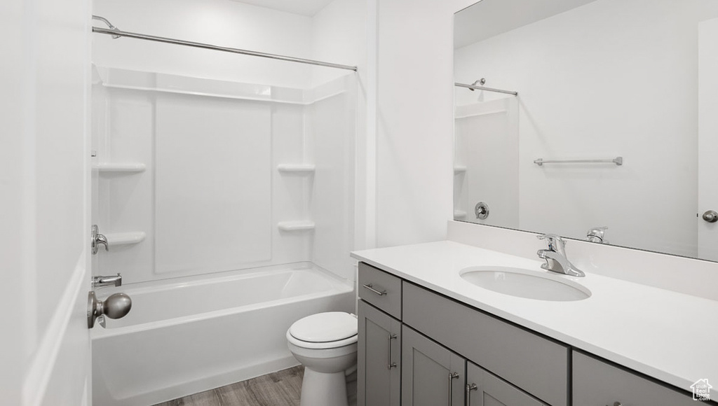 Bathroom featuring toilet, vanity, shower / bathing tub combination, and wood finished floors