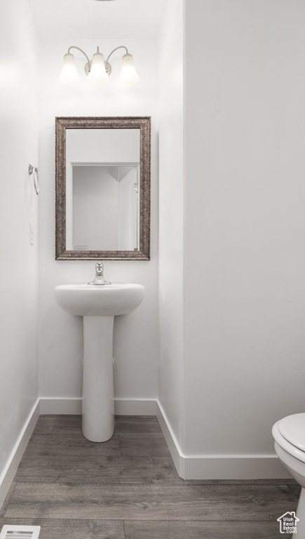 Half bath featuring toilet, baseboards, and wood finished floors