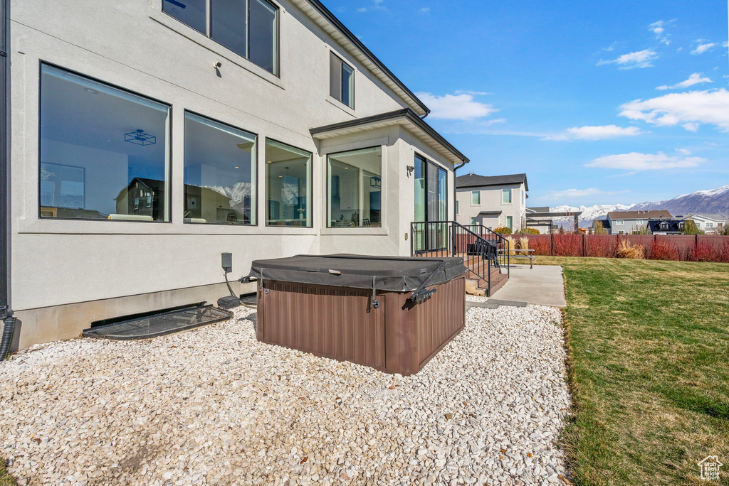 View of yard featuring a hot tub, fence, a mountain view, and a patio area