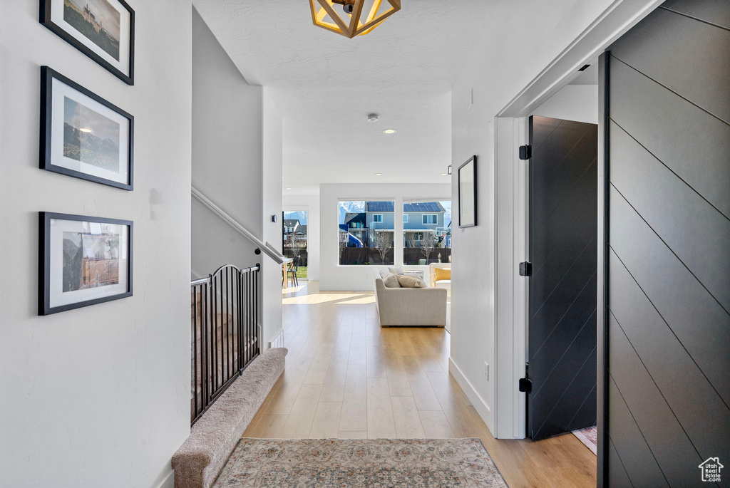 Corridor with an upstairs landing, light wood-style floors, and recessed lighting