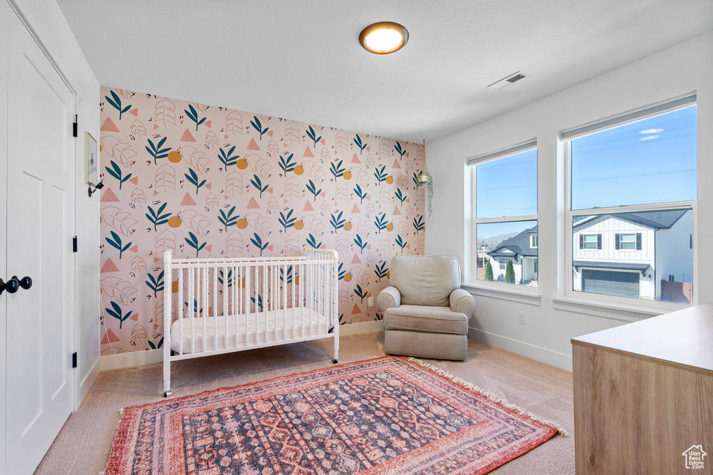 Carpeted bedroom with baseboards, wallpapered walls, and visible vents