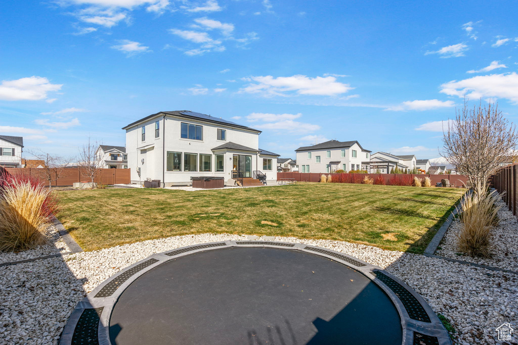 Back of property with a fenced backyard, a patio, a residential view, and roof mounted solar panels