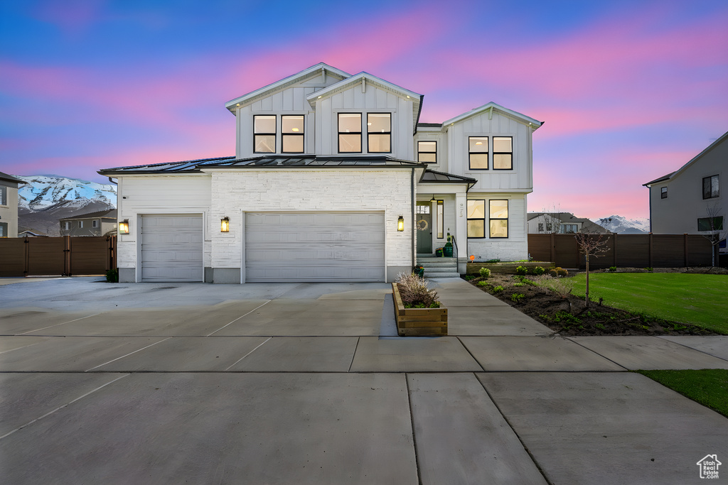 Modern inspired farmhouse with driveway, a standing seam roof, fence, and metal roof