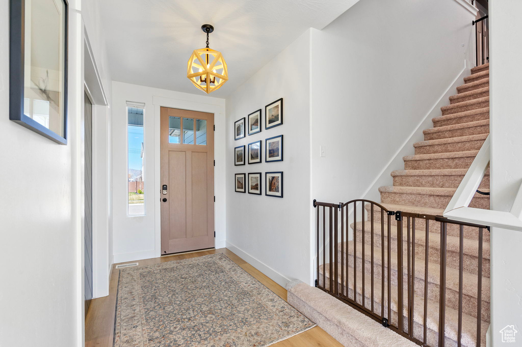 Entryway featuring baseboards, wood finished floors, stairway, and a chandelier