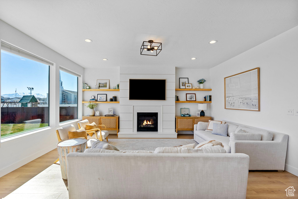 Living area featuring light wood finished floors, baseboards, recessed lighting, and a large fireplace