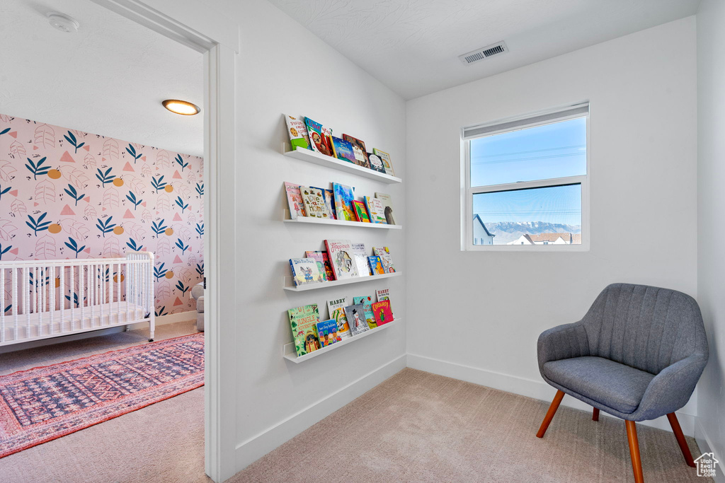 Living area featuring baseboards, visible vents, wallpapered walls, and carpet