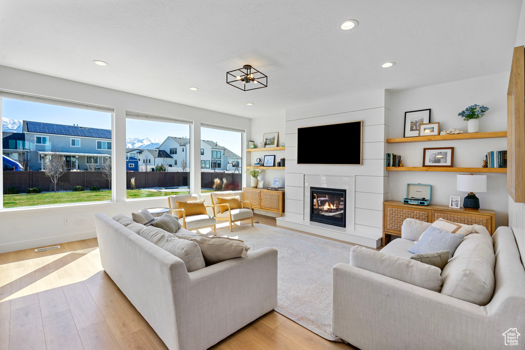 Living area featuring a glass covered fireplace, baseboards, light wood finished floors, and recessed lighting