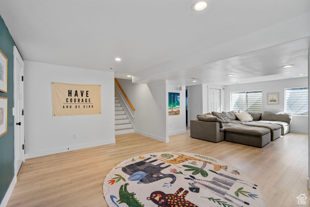 Living room featuring baseboards, stairs, light wood-style flooring, and recessed lighting