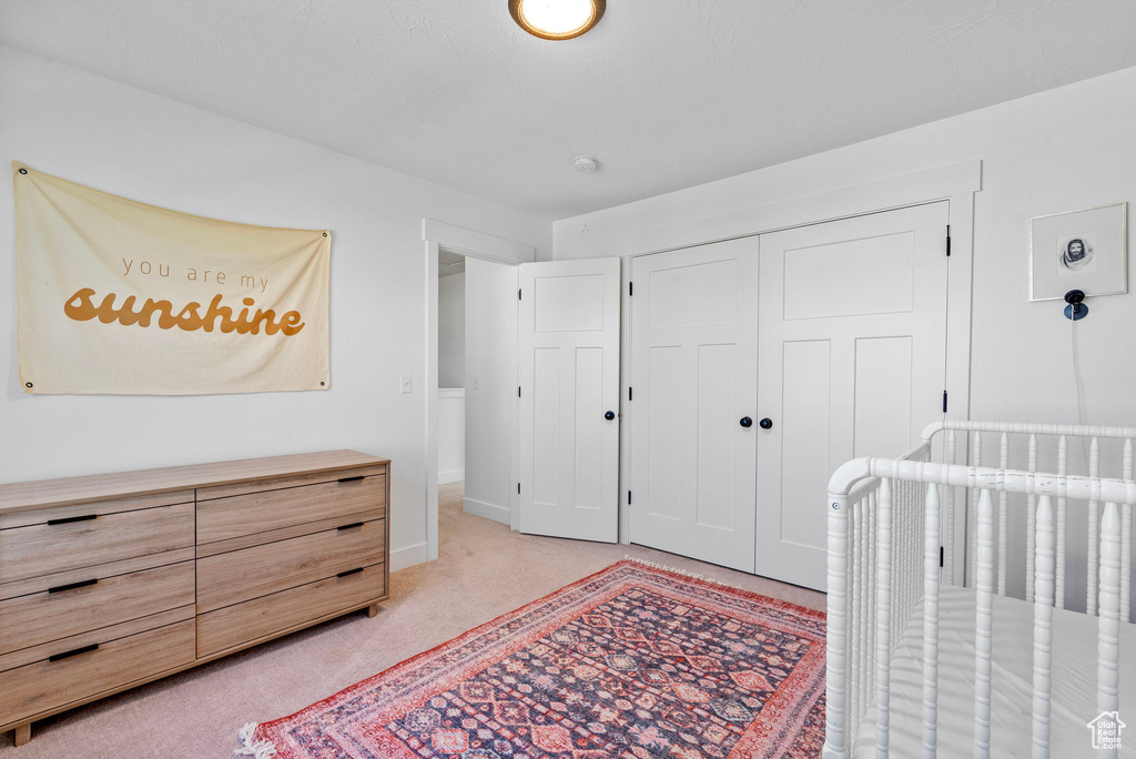 Bedroom with a closet, light carpet, and baseboards