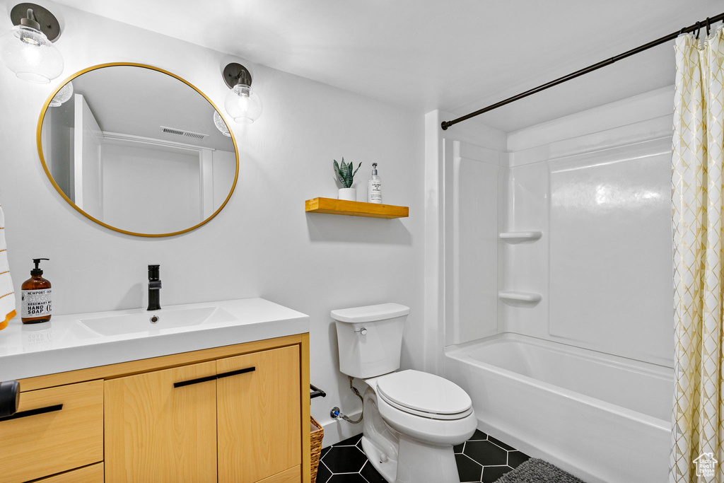 Full bath with tile patterned floors, toilet, vanity, shower / bath combo with shower curtain, and visible vents