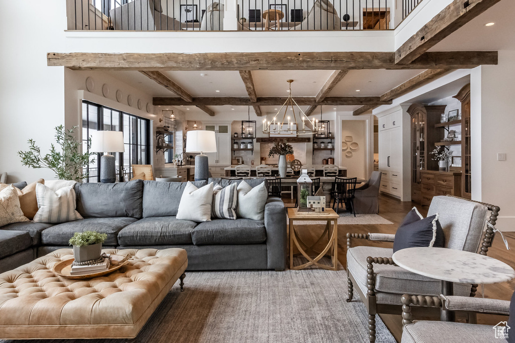 Living room with a chandelier, beam ceiling, and wood finished floors