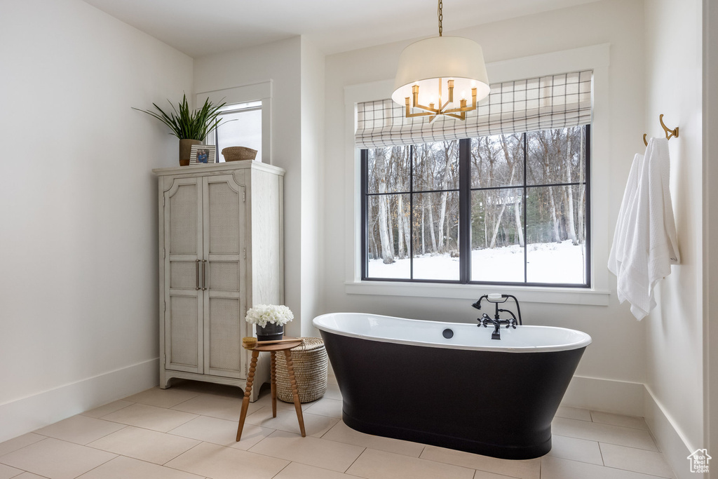 Full bath with a freestanding tub, a chandelier, baseboards, and tile patterned floors