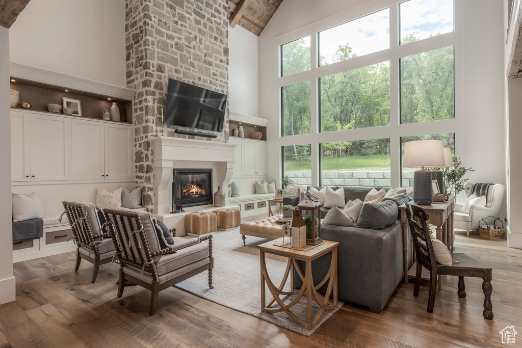Living room featuring high vaulted ceiling, hardwood / wood-style floors, a large fireplace, and beam ceiling