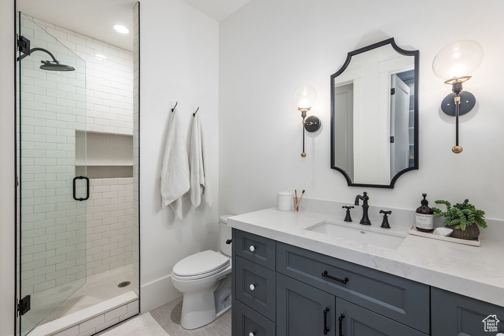 Bathroom featuring toilet, vanity, and a shower stall