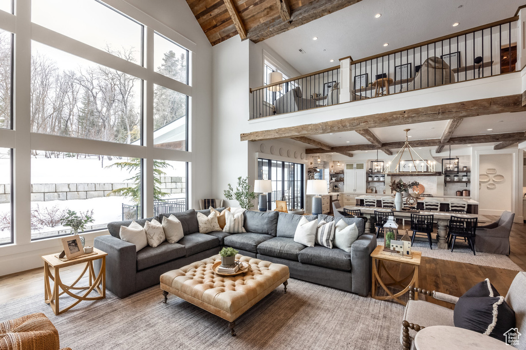 Living room featuring wood finished floors, beamed ceiling, healthy amount of natural light, a high ceiling, and recessed lighting