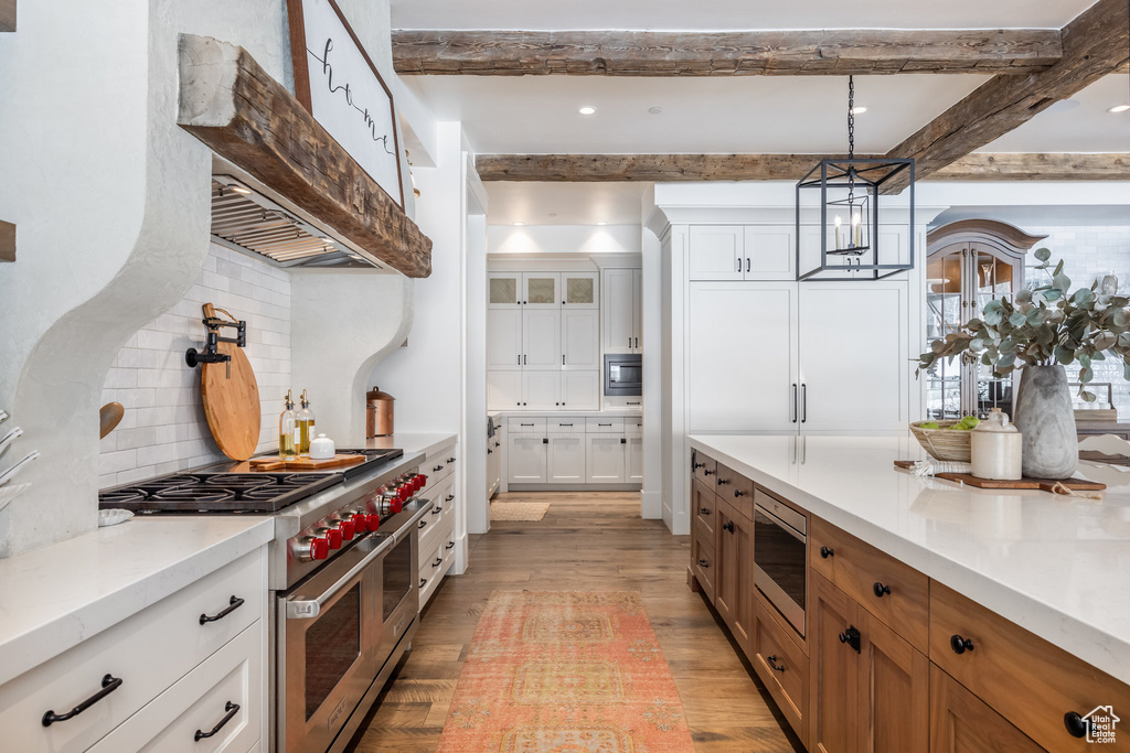 Kitchen with stainless steel appliances, light wood finished floors, decorative backsplash, light countertops, and beamed ceiling