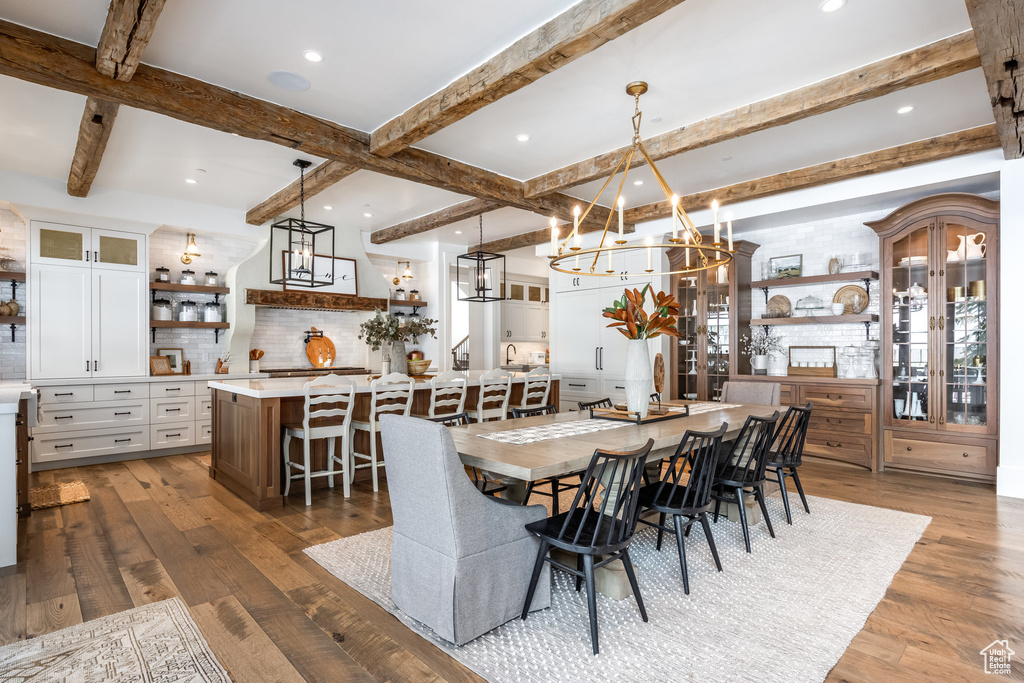 Dining space featuring a chandelier, wood finished floors, beam ceiling, and recessed lighting