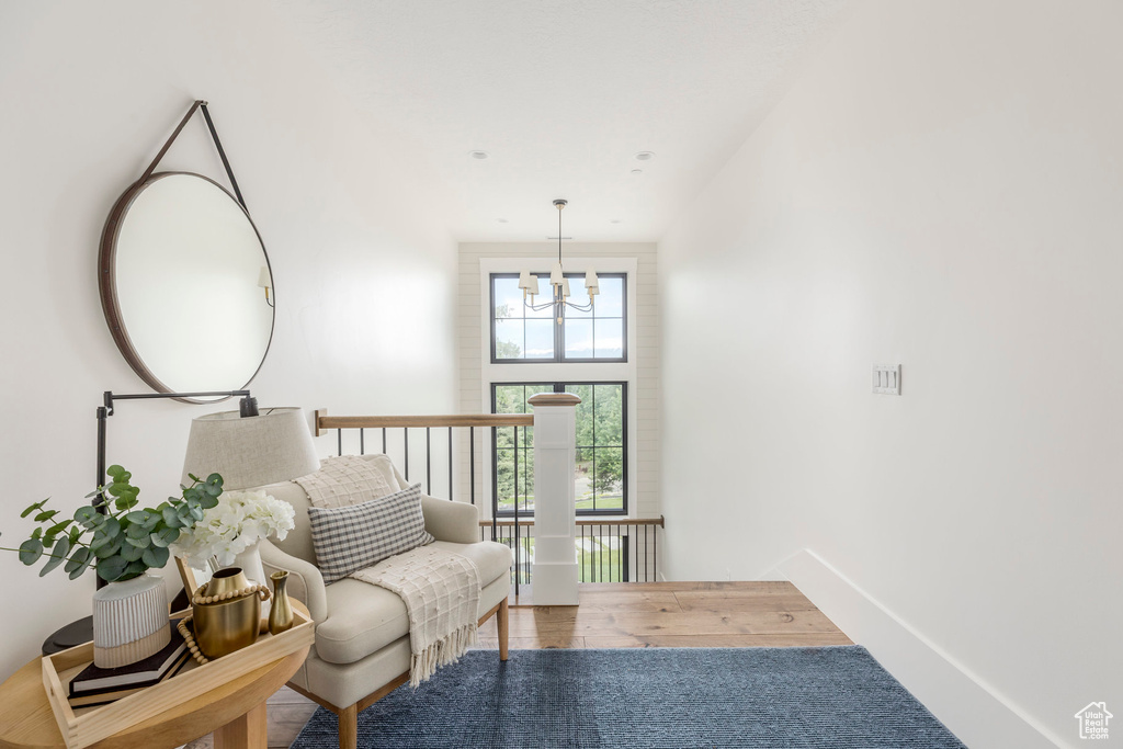Living area with a chandelier, wood finished floors, and an upstairs landing