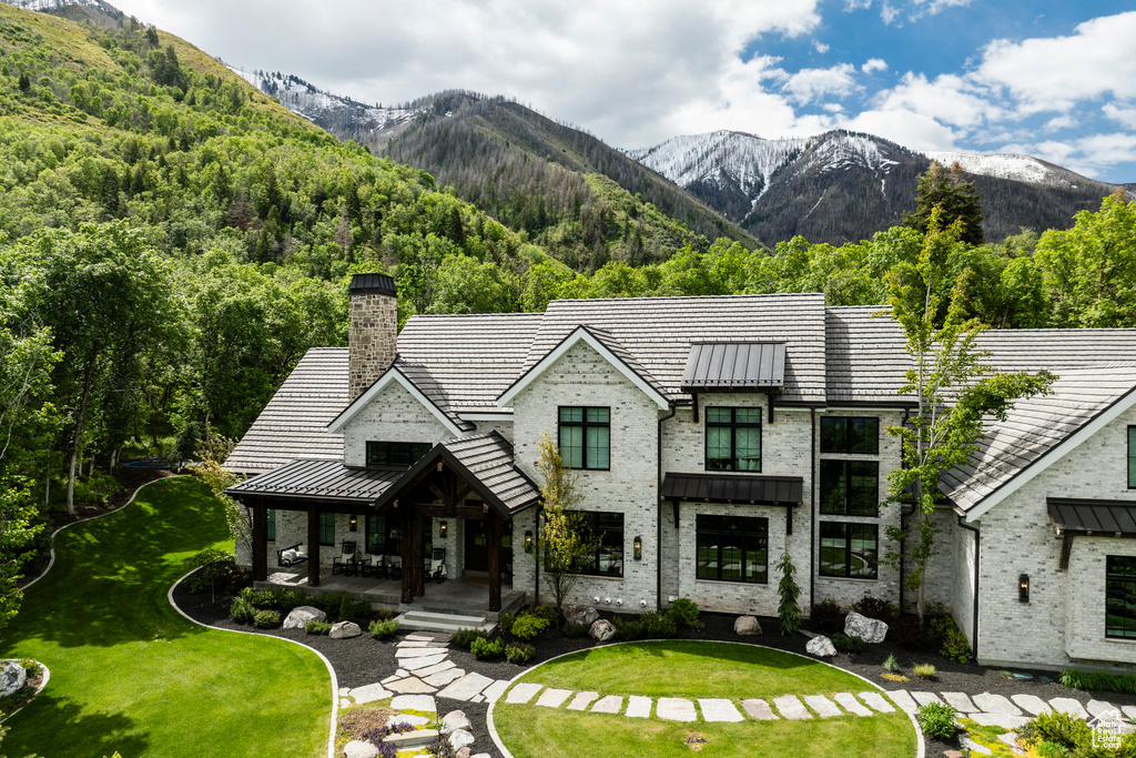 View of front facade featuring covered porch, a standing seam roof, a mountain view, and a chimney