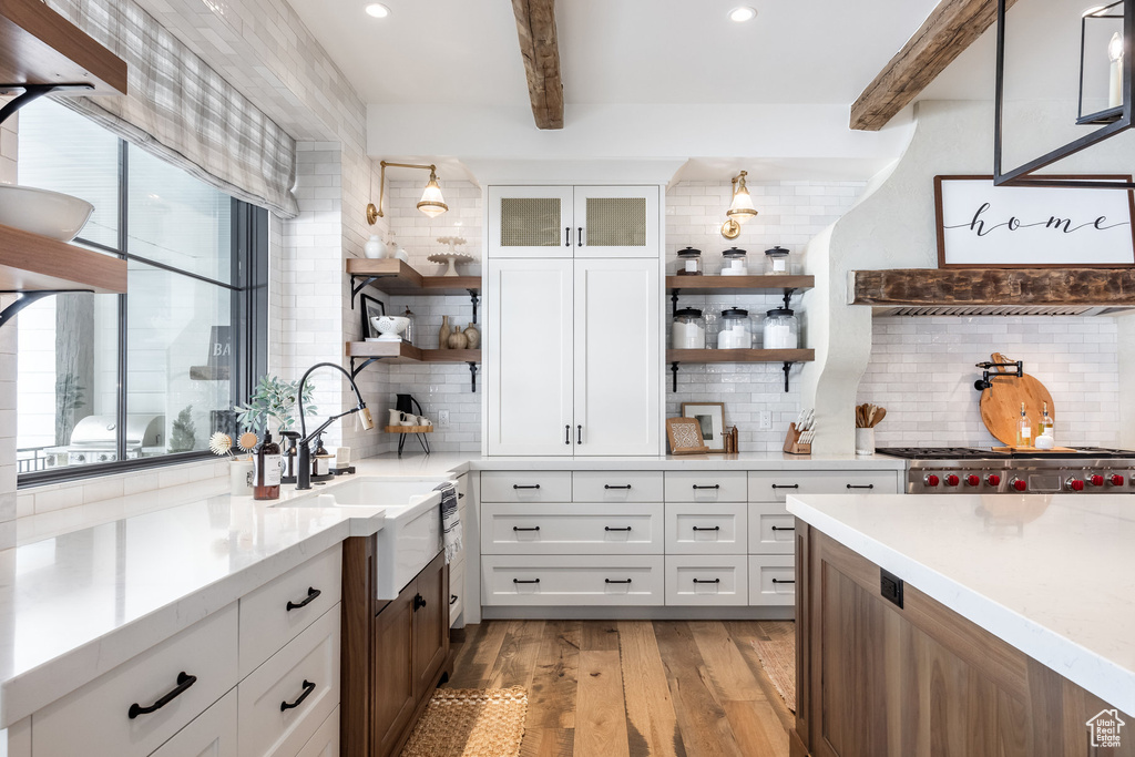 Kitchen with open shelves, beam ceiling, decorative backsplash, light countertops, and light wood-type flooring