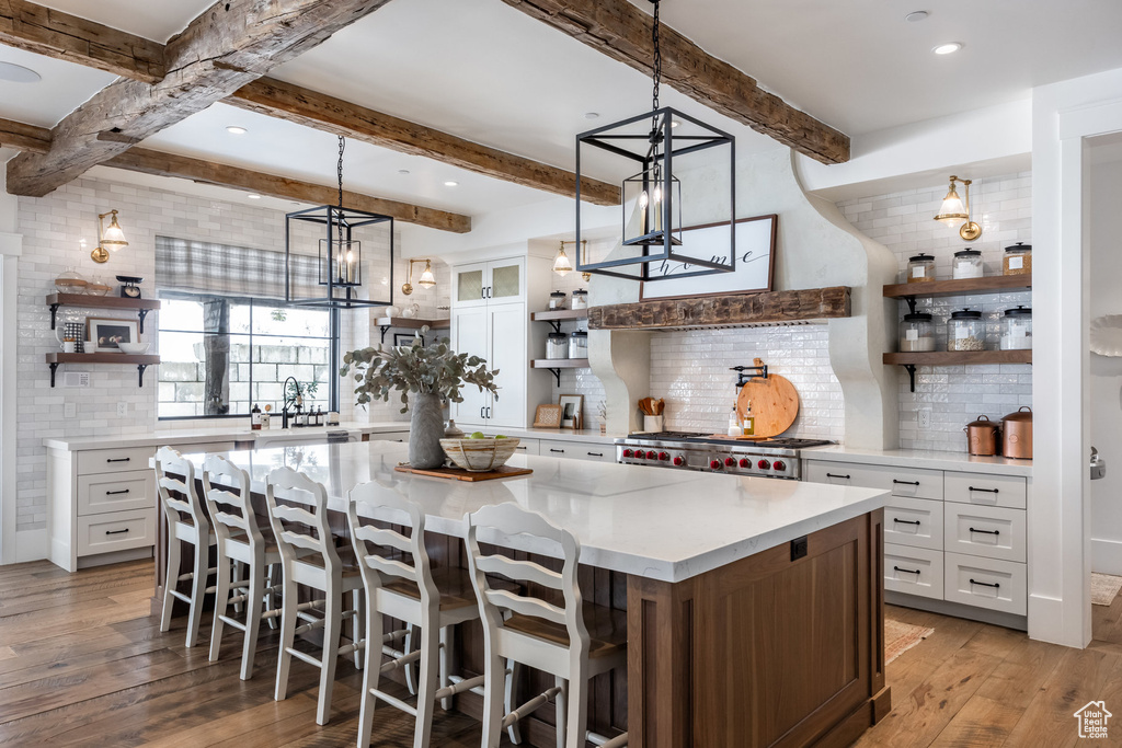 Kitchen with open shelves, decorative backsplash, light wood finished floors, range, and beam ceiling
