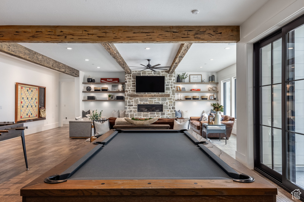 Rec room with ceiling fan, wood finished floors, beam ceiling, and a fireplace