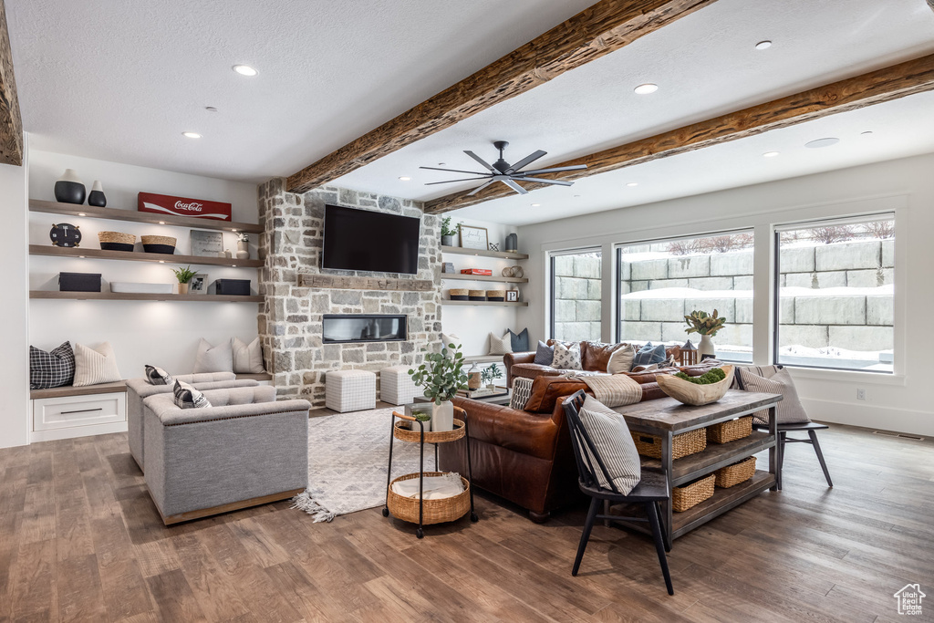 Living room with wood finished floors, a fireplace, ceiling fan, beamed ceiling, and recessed lighting