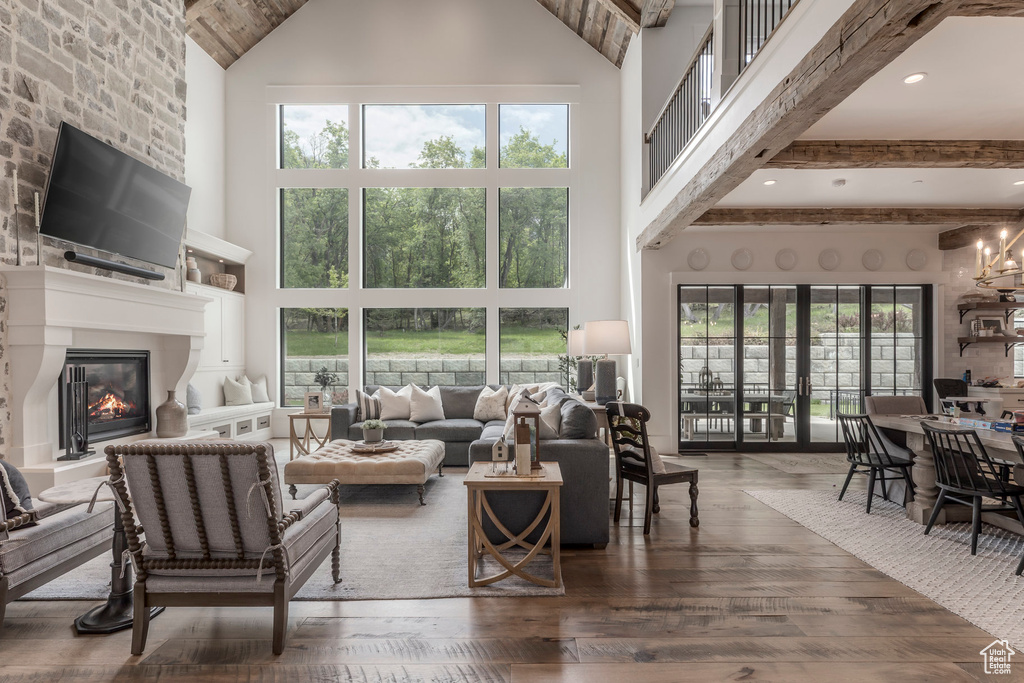 Living area with high vaulted ceiling, a fireplace, wood-type flooring, and healthy amount of natural light