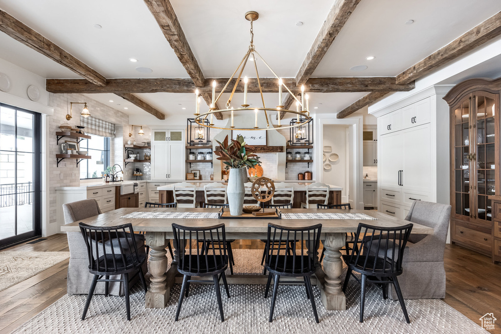 Dining area with wood-type flooring, a chandelier, and beamed ceiling
