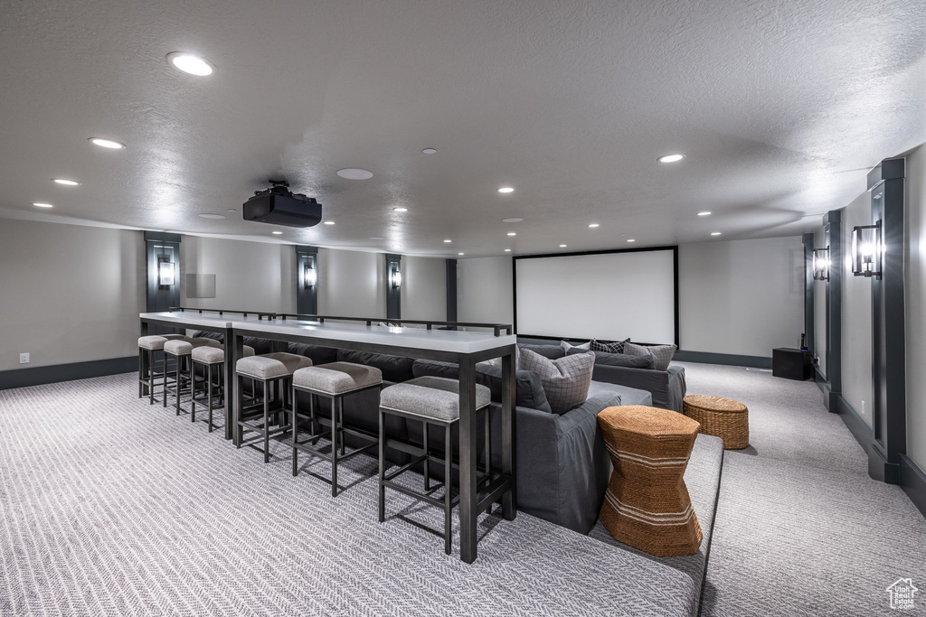 Home theater featuring light colored carpet, baseboards, recessed lighting, a dry bar, and a textured ceiling