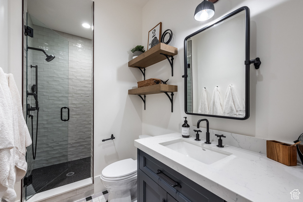 Bathroom featuring toilet, vanity, and a stall shower