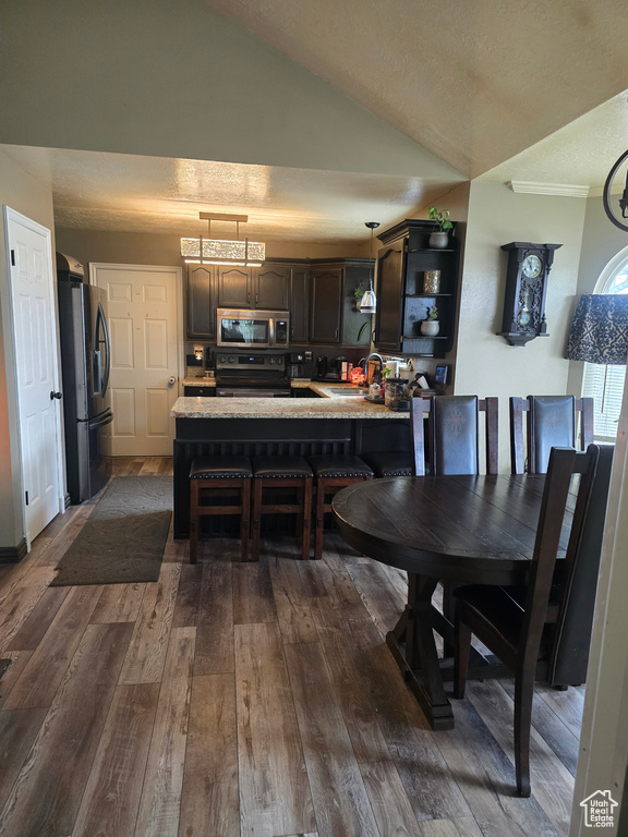 Dining room featuring dark wood finished floors, crown molding, and lofted ceiling