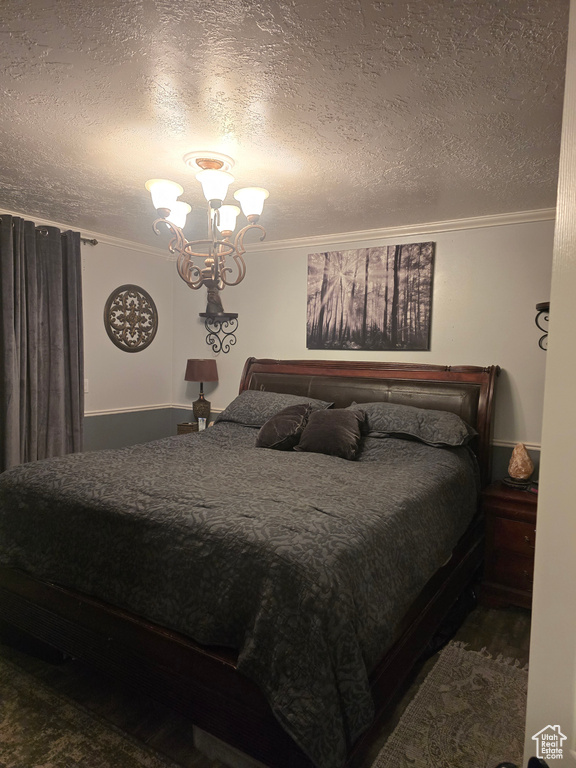Bedroom featuring a textured ceiling, an inviting chandelier, and ornamental molding