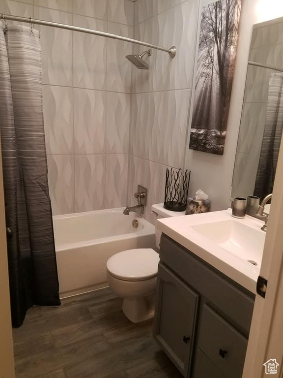 Full bath with vanity, toilet, wood finished floors, and shower / bath combo