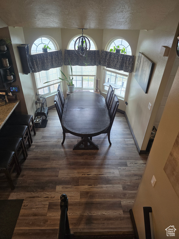 Dining room featuring baseboards, a textured ceiling, and wood finished floors