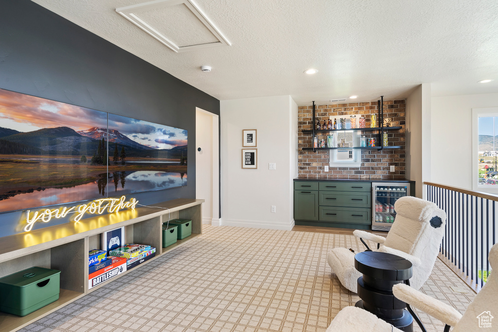 Interior space with wine cooler, attic access, a textured ceiling, a bar, and baseboards